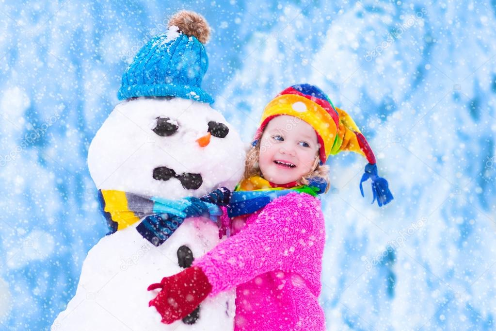 Little girl playing with a snowman