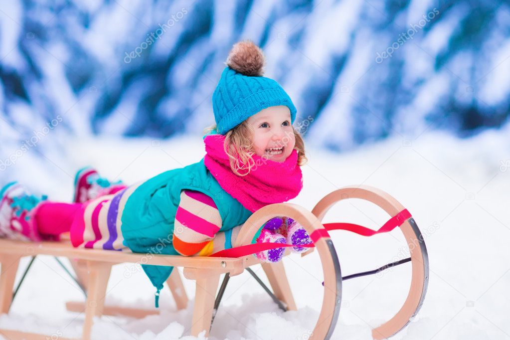 Little girl playing in snowy winter forest