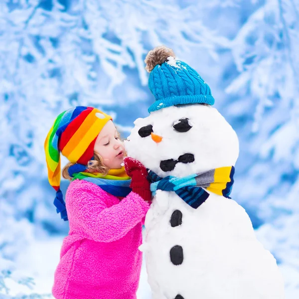 Petite fille construisant un bonhomme de neige en hiver — Photo