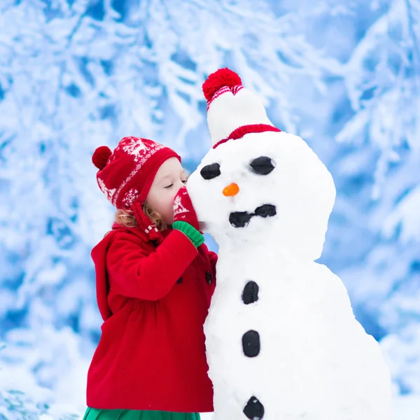 Mała dziewczynka budynku człowiek śniegu — Zdjęcie stockowe
