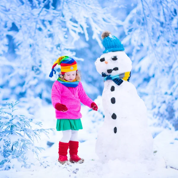 Kleines Mädchen baut im Winter einen Schneemann — Stockfoto