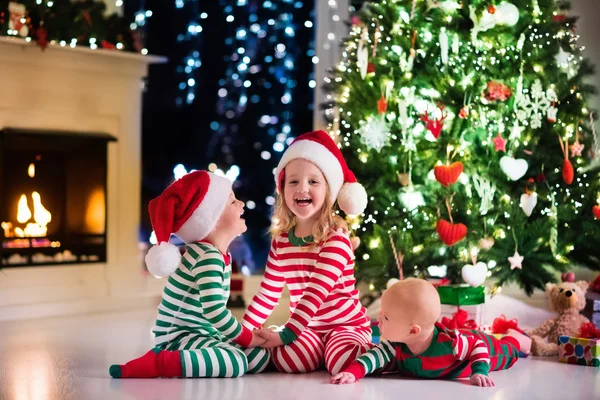 Barn i pyjamas under julgranen — Stockfoto