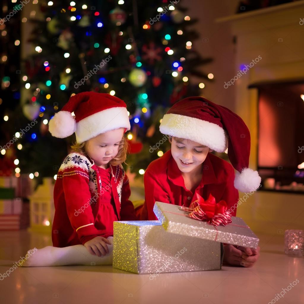 Bimbi Che Aprono I Regali Di Natale.Kids Opening Christmas Presents At Fireplace Stock Photo C Famveldman 126900102