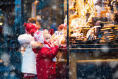 Kinder schauen sich auf Weihnachtsmarkt Süßigkeiten und Gebäck an