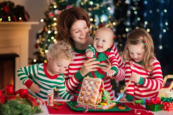 母と子供たちのクリスマスのジンジャーブレッドの家を作る — ストック写真