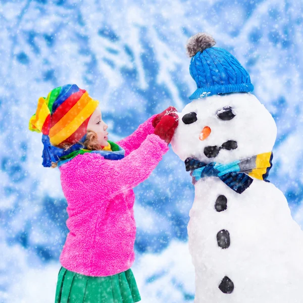 Menina construindo um homem de neve no inverno — Fotografia de Stock