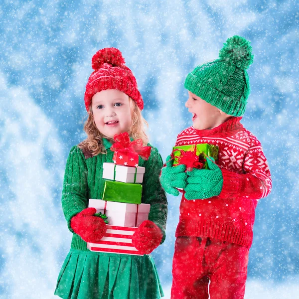 Kids with Christmas presents in winter park in snow — Stock Photo, Image