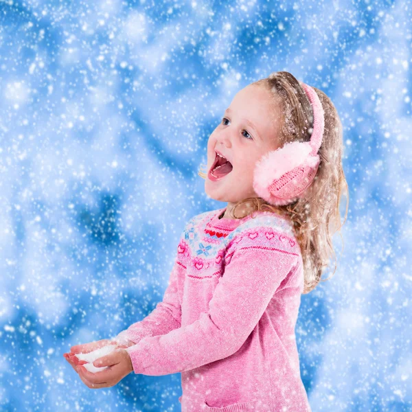 Little girl catching snow flakes