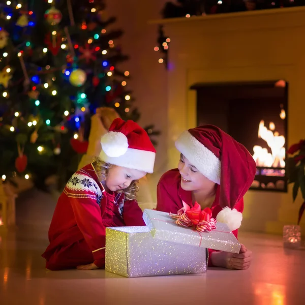 Crianças abrindo presentes de Natal na lareira — Fotografia de Stock