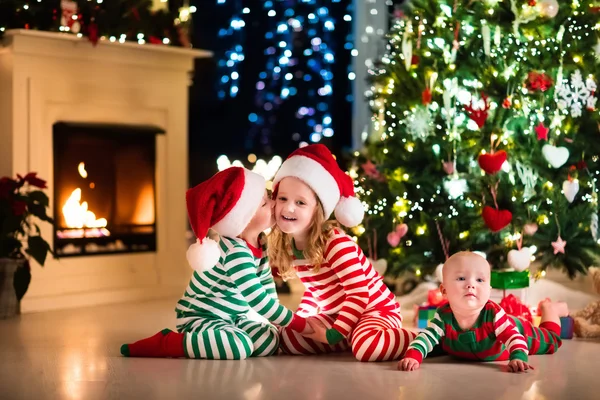 Barn i pyjamas under julgranen — Stockfoto