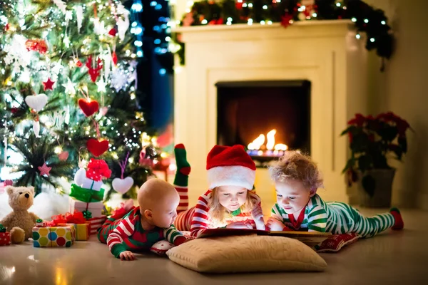 Crianças de pijama debaixo da árvore de Natal — Fotografia de Stock