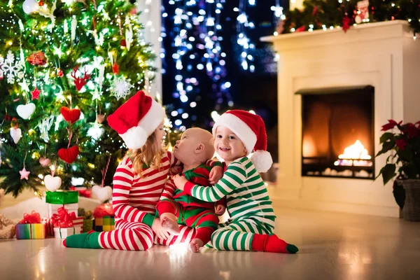 Barn i pyjamas under julgranen — Stockfoto