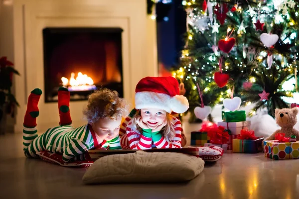 Děti v pyžamu pod vánoční stromeček — Stock fotografie