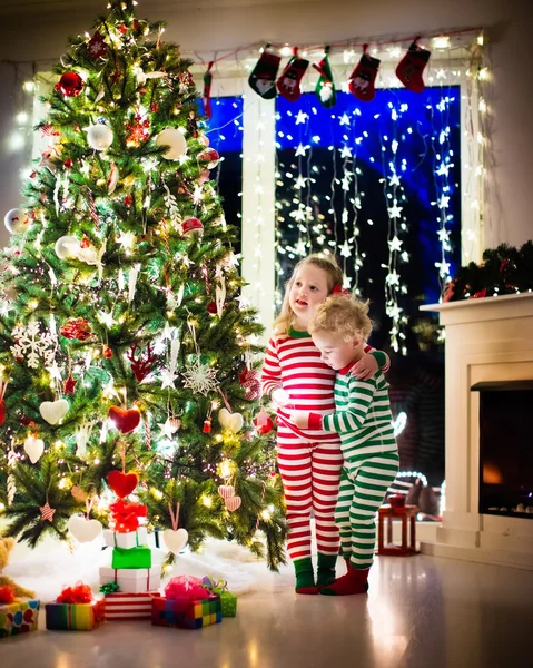 Τα παιδιά με τις πυτζάμες κάτω από το χριστουγεννιάτικο δέντρο — Φωτογραφία Αρχείου