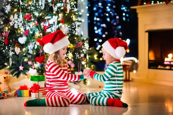Crianças de pijama debaixo da árvore de Natal — Fotografia de Stock