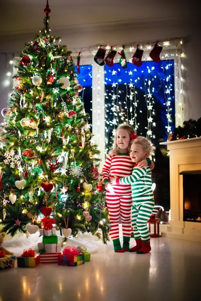 Τα παιδιά με τις πυτζάμες κάτω από το χριστουγεννιάτικο δέντρο — Φωτογραφία Αρχείου