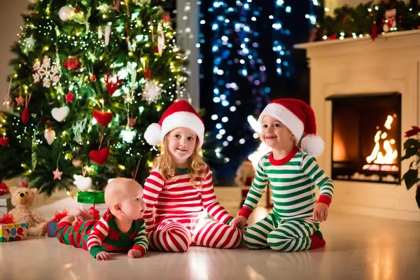 Barn i pyjamas under julgranen — Stockfoto