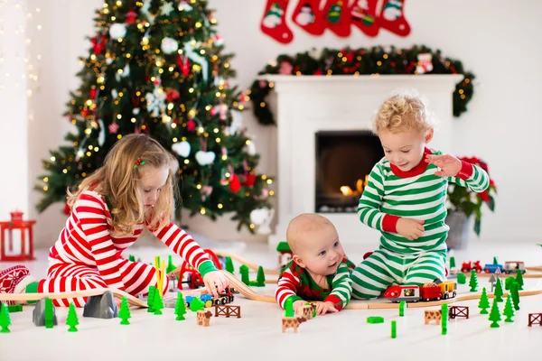 Bambini che giocano con la ferrovia giocattolo la mattina di Natale — Foto Stock