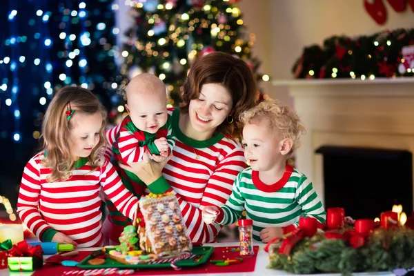 Madre e hijos haciendo casa de pan de jengibre en Navidad —  Fotos de Stock