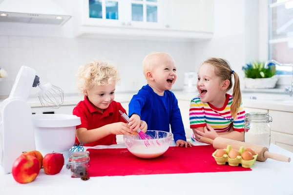 Дети пекут пирог на белой кухне — стоковое фото
