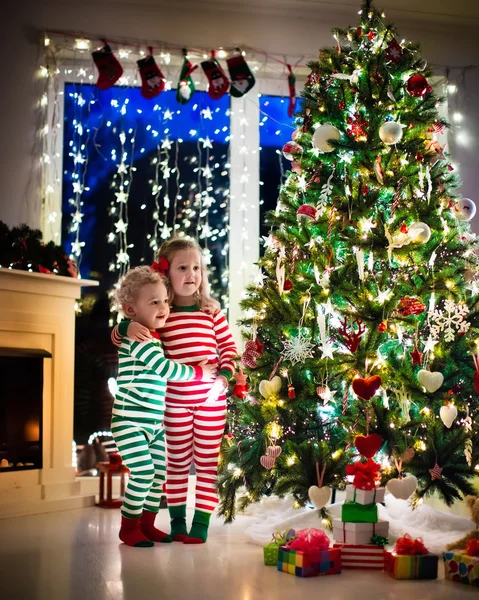 Niños en pijama bajo el árbol de Navidad — Foto de Stock