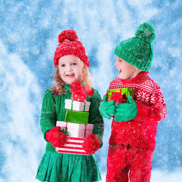 Kids with Christmas presents in snowy winter park — Stock Photo, Image