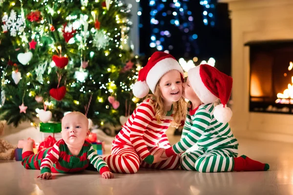 Barn i pyjamas under julgranen — Stockfoto