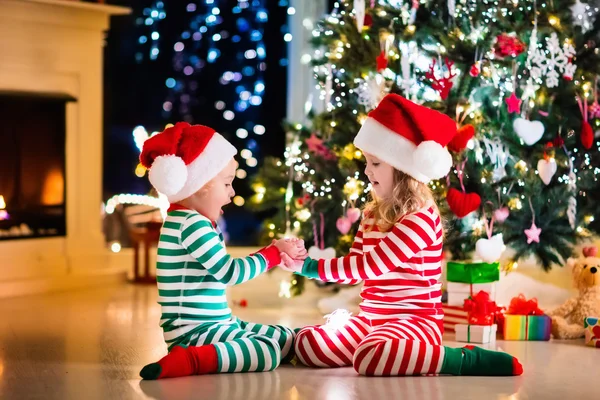 Barn i pyjamas under julgranen — Stockfoto