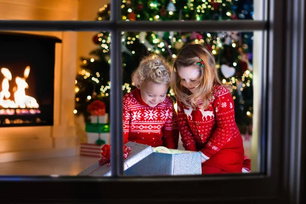 Niños abriendo regalos de Navidad en la chimenea — Foto de Stock