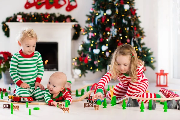 Niños jugando con el ferrocarril de juguete en la mañana de Navidad — Foto de Stock