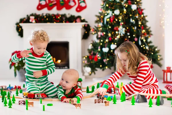 Niños jugando con el ferrocarril de juguete en la mañana de Navidad — Foto de Stock