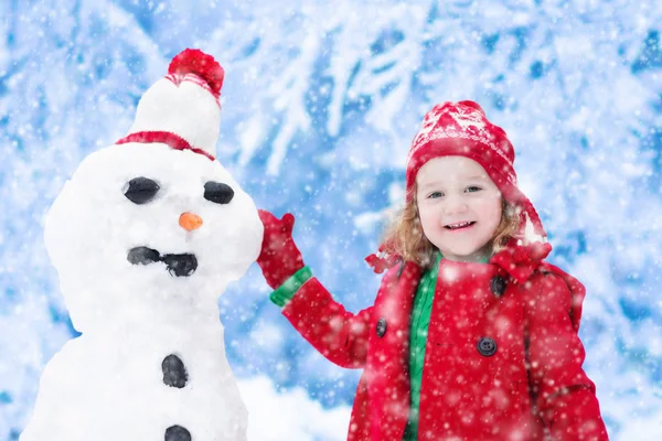Malá holčička budování sněhu muž — Stock fotografie