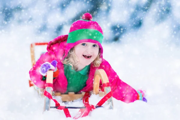 Lilla tjejen njuter av en släde på vintern — Stockfoto