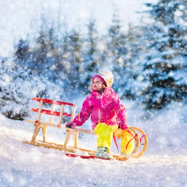 Mała dziewczynka zabawy na sanki w mroźną zimę z lasu — Zdjęcie stockowe