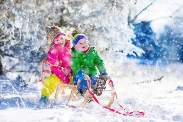 Crianças montando um trenó no parque de inverno nevado — Fotografia de Stock