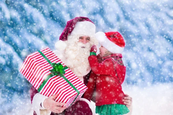 Jultomten pratar med liten flicka i snöig park — Stockfoto