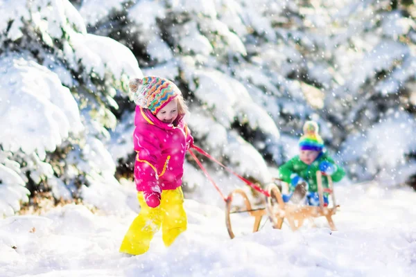 Дети катаются на санях в снежном зимнем парке — стоковое фото