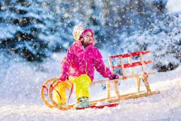 Küçük kız karlı kış ormandaki bir kızak üzerinde eğleniyor — Stok fotoğraf