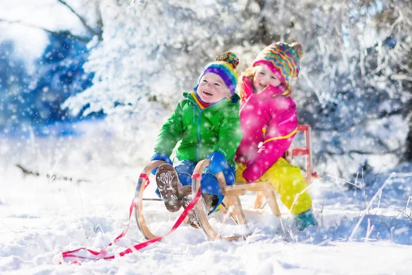 孩子们骑在白雪皑皑的冬季公园的雪橇 — 图库照片