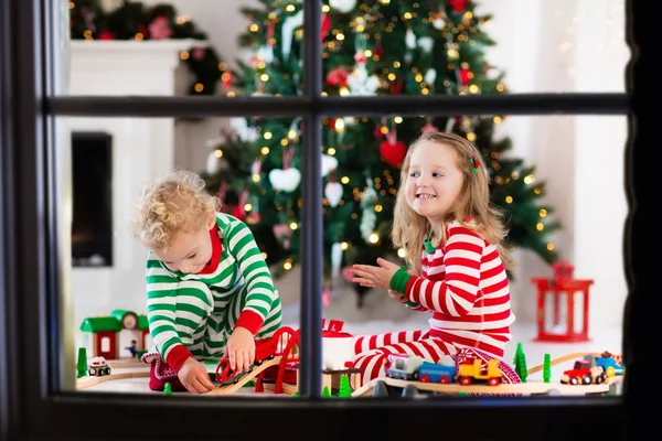 Crianças brincando com brinquedo ferroviário na manhã de Natal — Fotografia de Stock