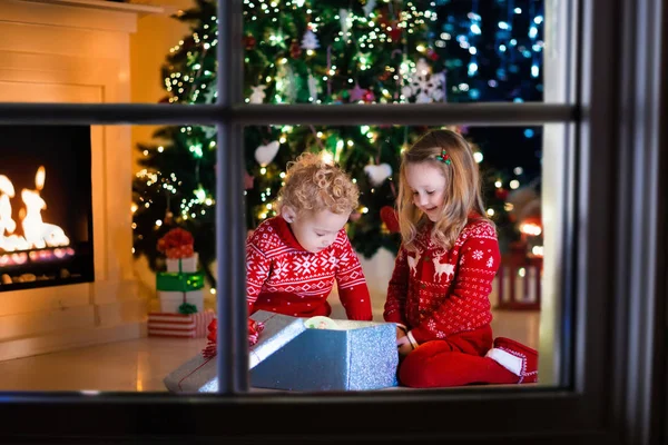 Kids opening Christmas presents at fireplace — Stock Photo, Image