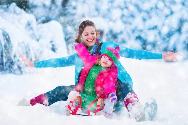 Madre e hijo en trineo en un parque cubierto de nieve — Foto de Stock