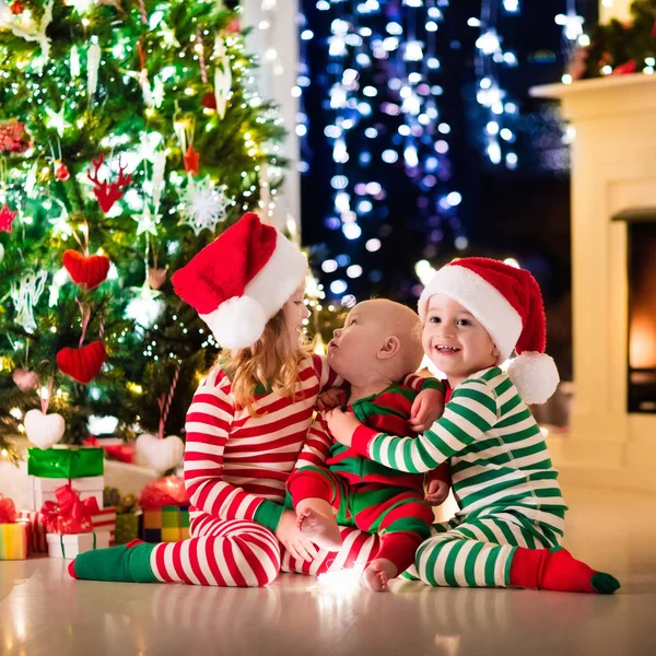 Niños en pijama bajo el árbol de Navidad —  Fotos de Stock