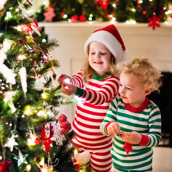 Kids in pajamas under Christmas tree — Stock Photo, Image