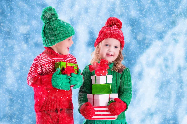Kids with Christmas presents in winter park in snow — Stock Photo, Image