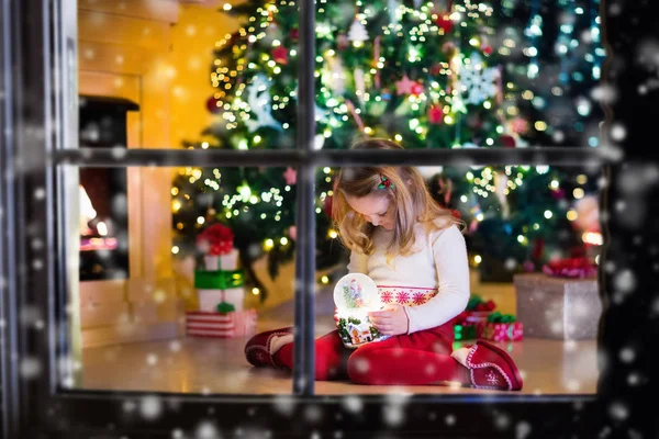 Kar küresi Noel ağacının altında tutan küçük kız — Stok fotoğraf