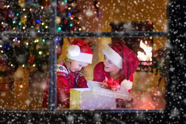 Дети открывают рождественские подарки у камина — стоковое фото