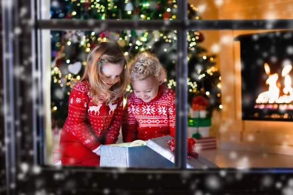 Kinder öffnen Weihnachtsgeschenke am Kamin — Stockfoto