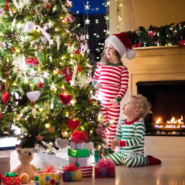 Anak-anak dengan piyama di bawah pohon Natal — Stok Foto