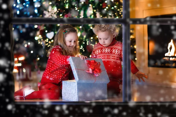暖炉のそばでクリスマス プレゼントを開ける子供 — ストック写真